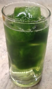 Frozen wheatgrass cubes in a glass of water.
