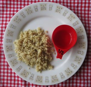 Cooked quinoa on plate with measuring cup.