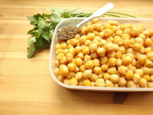 Cooked chickpeas in container with spoonful of cumin