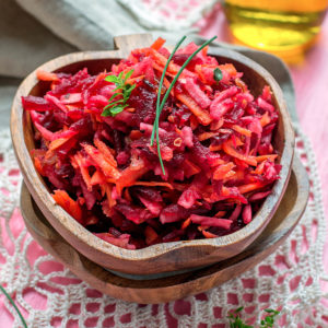 Grated beet and carrot salad on table with pink tablecloth & lace overlay.