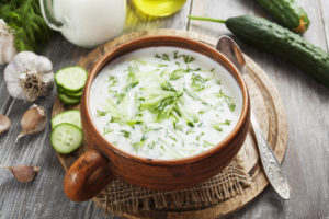 Cucumber and yogurt soup in small brown porcelain pot with handle. Garnished with dill.