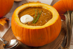 Pumpkin soup served in hollowed out pumpkin with chives and a dollop of sour cream on top.