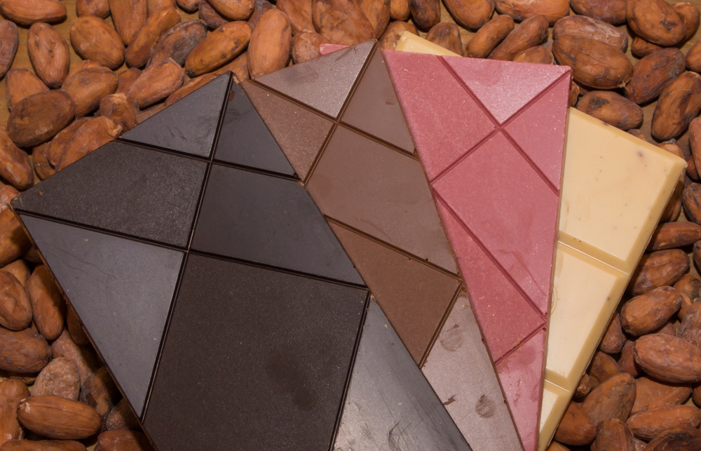 Chocolate bars - dark, milk, ruby and white on cocoa beans.