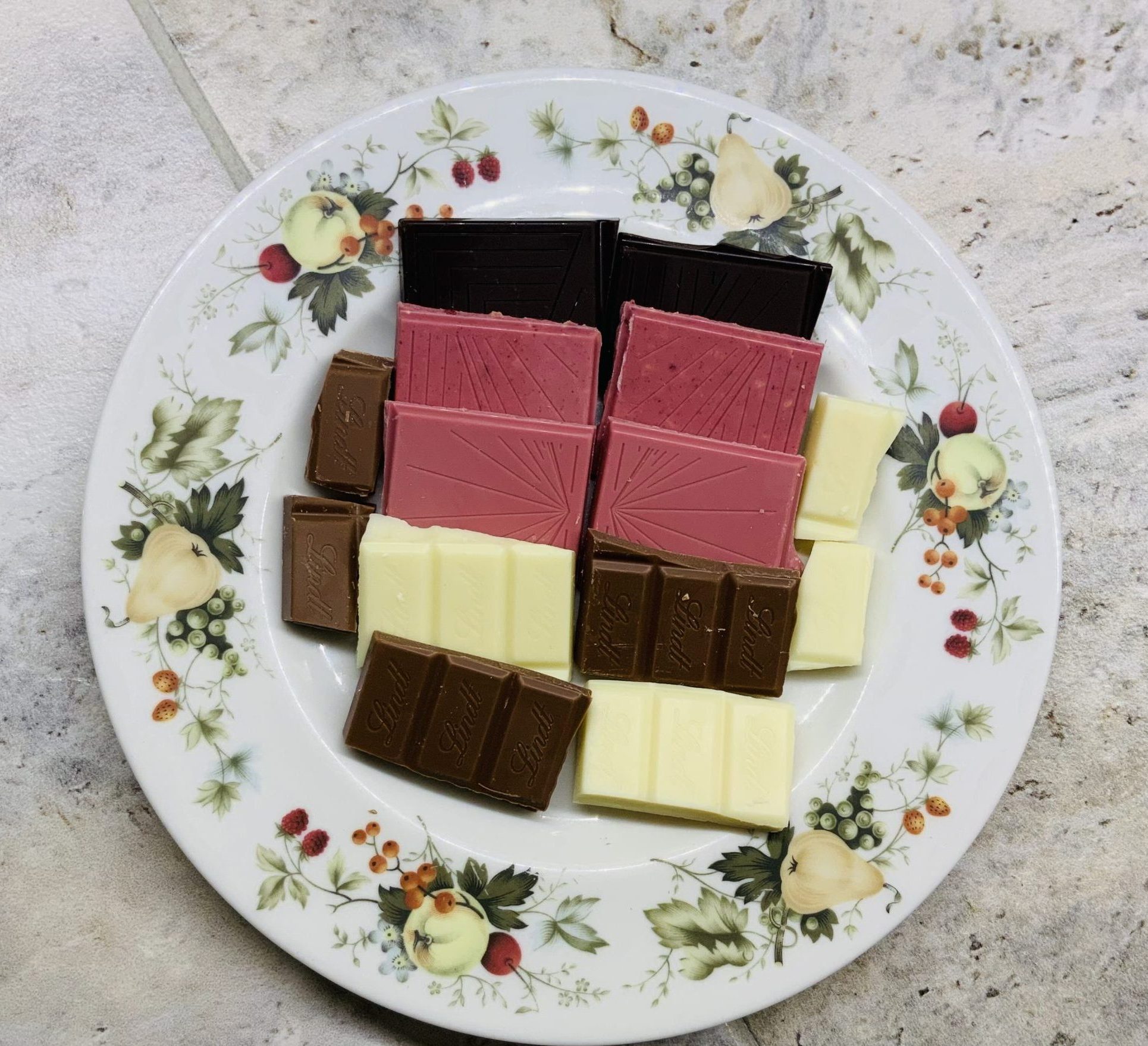 Pieces of dark, ruby, white and milk chocolate on a plate.