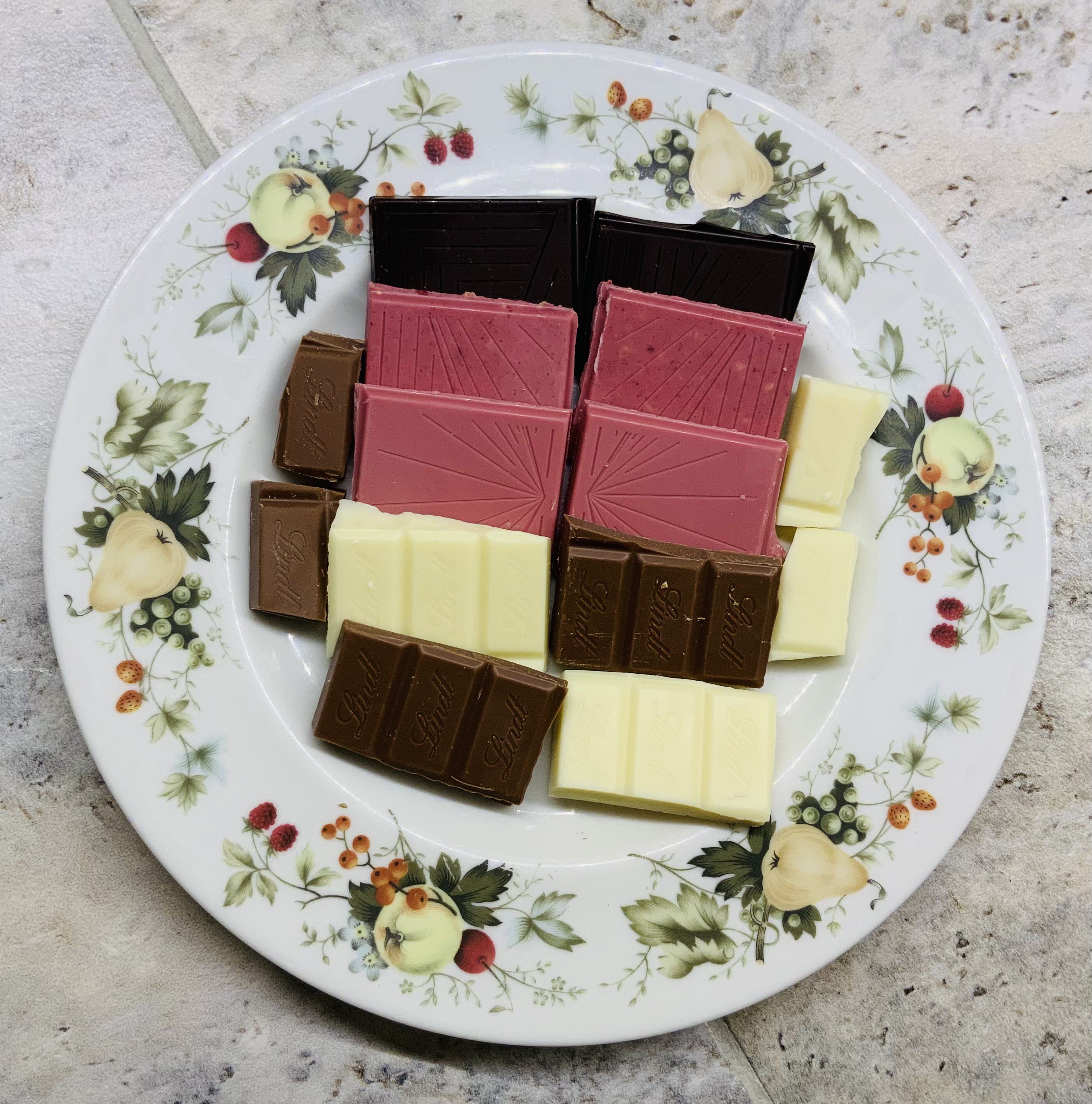 Pieces of dark, ruby, white and milk chocolate on a plate.