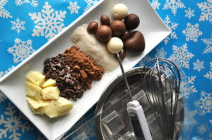 Ingredients and tools for making chocolates on winter background with snow flakes